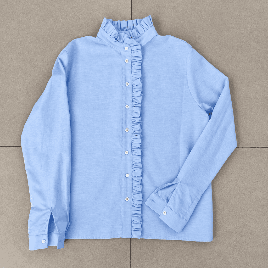 camicia azzurra con volant su piastrelle grigie