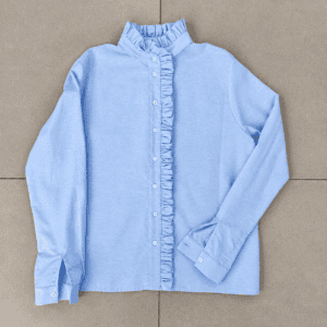 camicia azzurra con volant su piastrelle grigie
